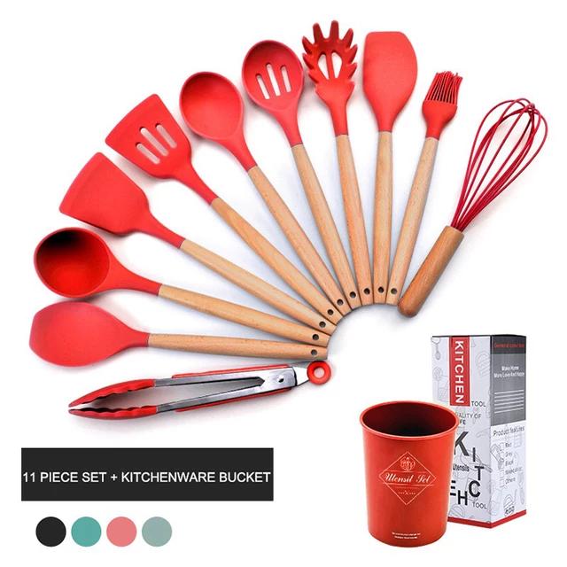 Set of red kitchen utensils with wooden handles, including spatulas, ladles, tongs, and a whisk, on a white background.